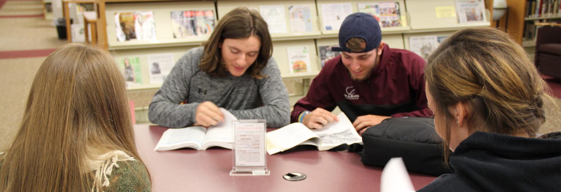 four students at a table in the library