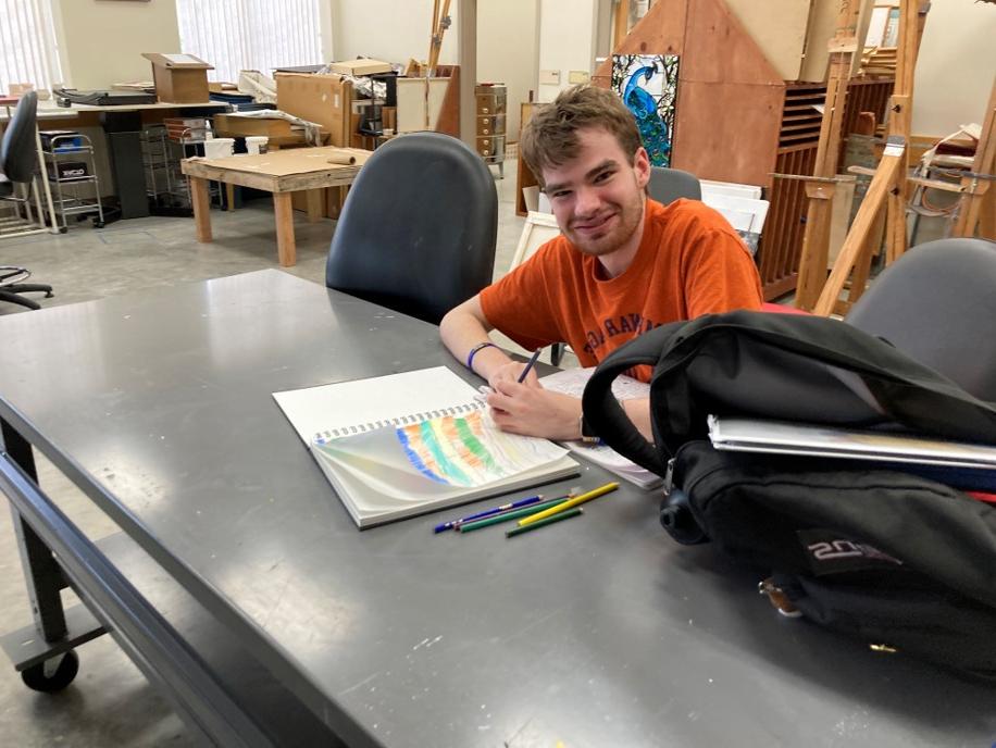 College for Life student proudly smiles at his artwork